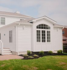 Bright white sunroom with large windows and a gable roof.